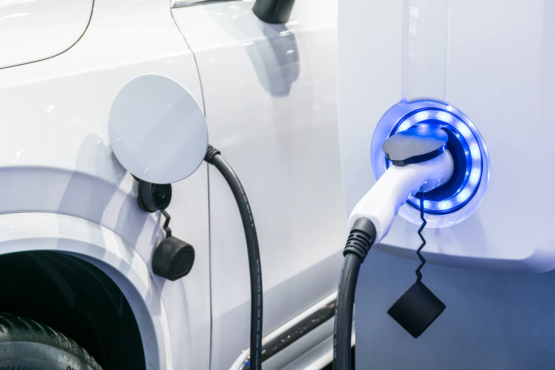 Extérieur jour, véhicule électrique blanc en cours de recharge sur station