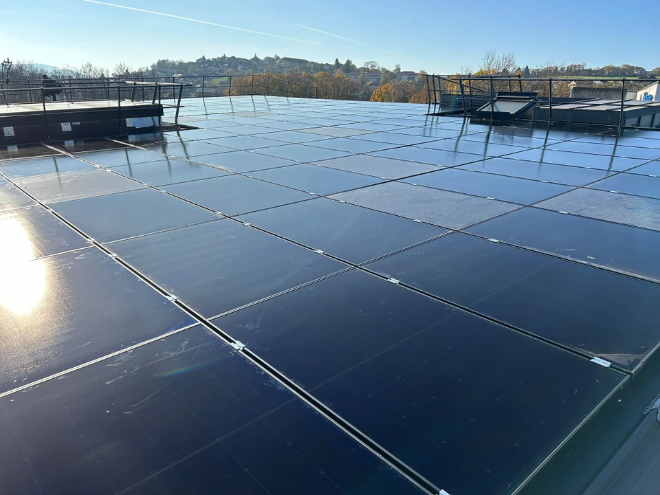 Ext&eacute;rieur, technicien avec gants noirs nettoie panneau solaire photovolta&iuml;que avec jet d'eau haute pression