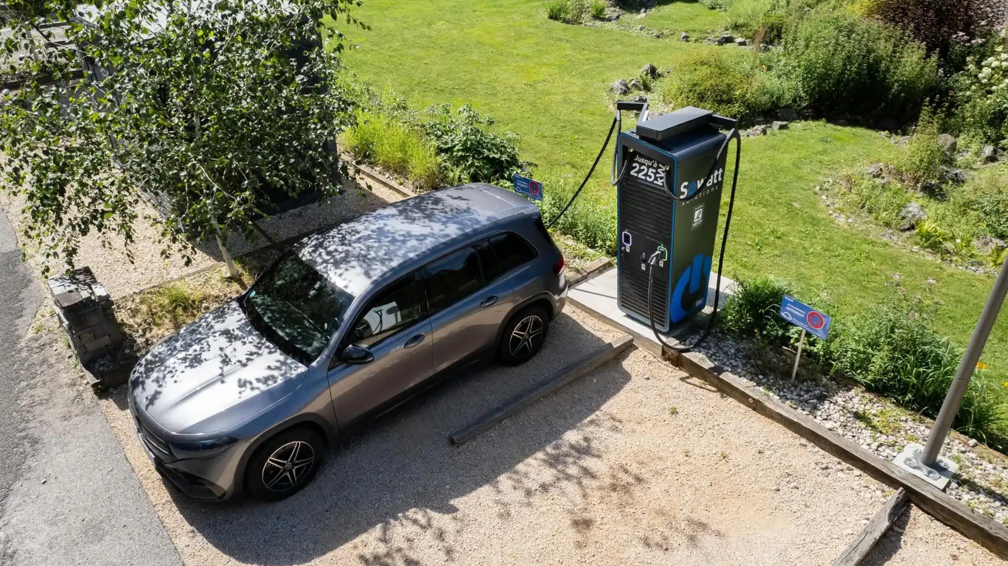 Extérieur jour, véhicule électrique blanc en cours de recharge sur station