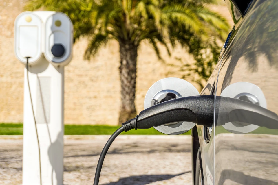 Technicien qualifié travaillant sur l'installation de la station de charge EV à domicile, effectuant le dépannage et la configuration sur le système de charge avec ordinateur portable pour EV à la maison