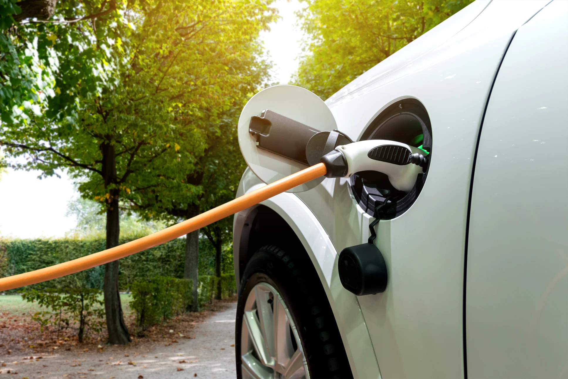 Scène extérieure d'une station de recharge pour véhicules électriques avec connecteurs branchés sur une voiture blanche